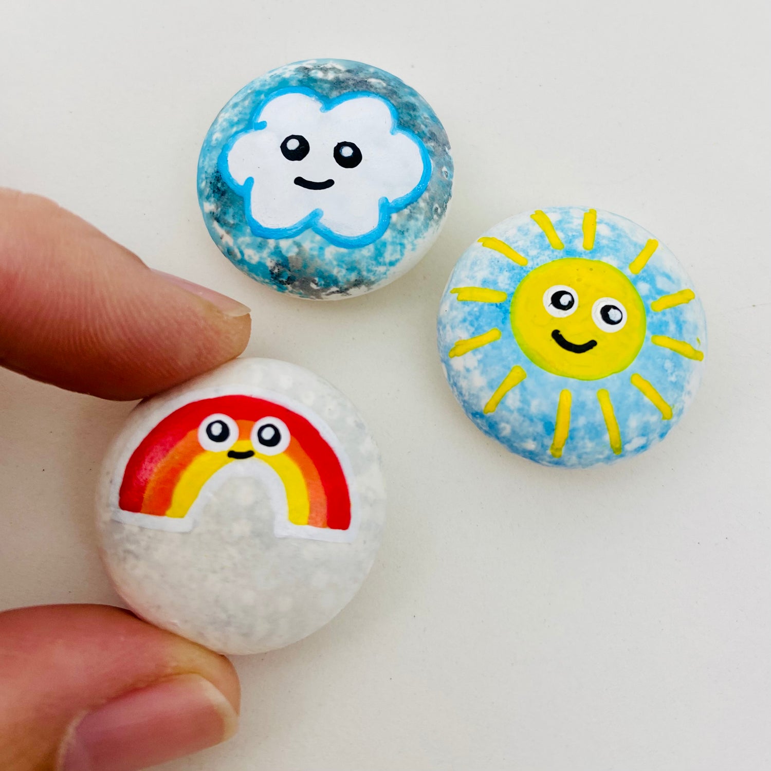 3 mini hand painted weather themed pebbles. A rainbow, Sunshine and Cloud.