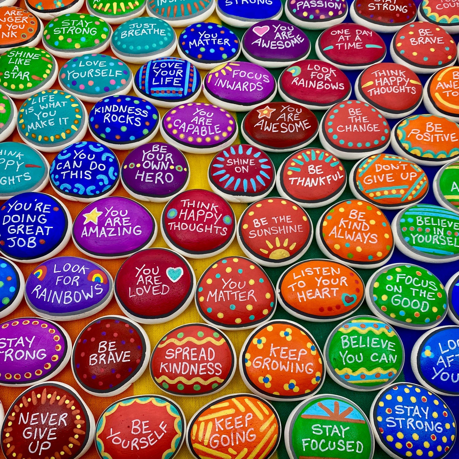 Lots of Colourful hand painted pebbles with affirmations written on