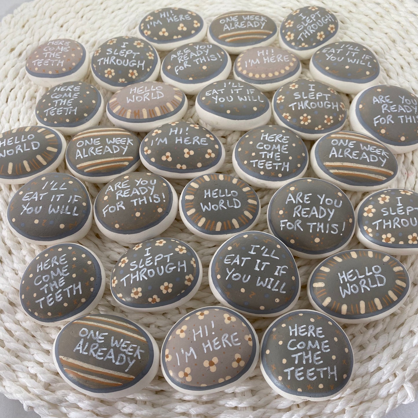 Lots of Neutral Coloured Hand painted pebbles with Baby Milestone words written on
