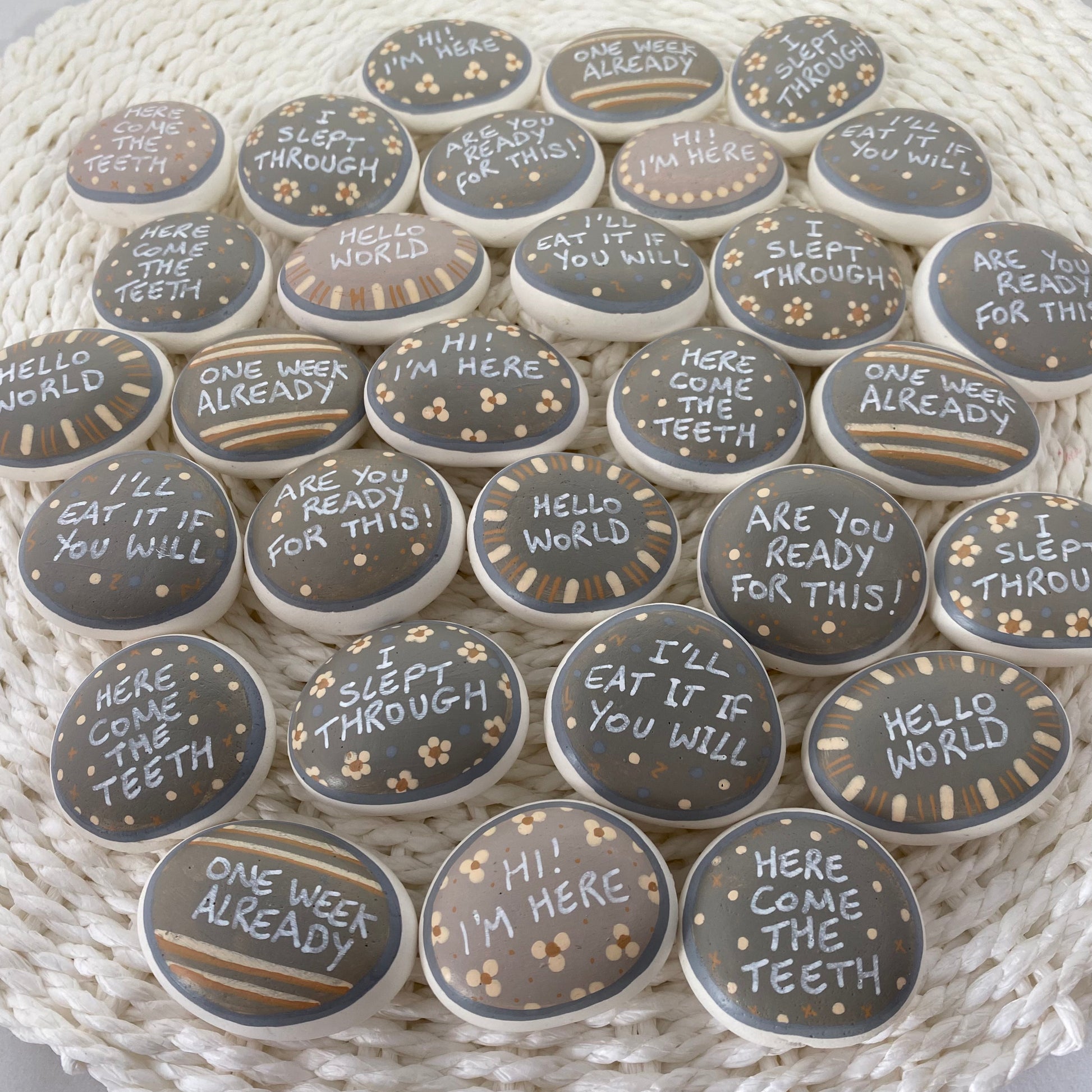 Lots of Neutral Coloured Hand painted pebbles with Baby Milestone words written on