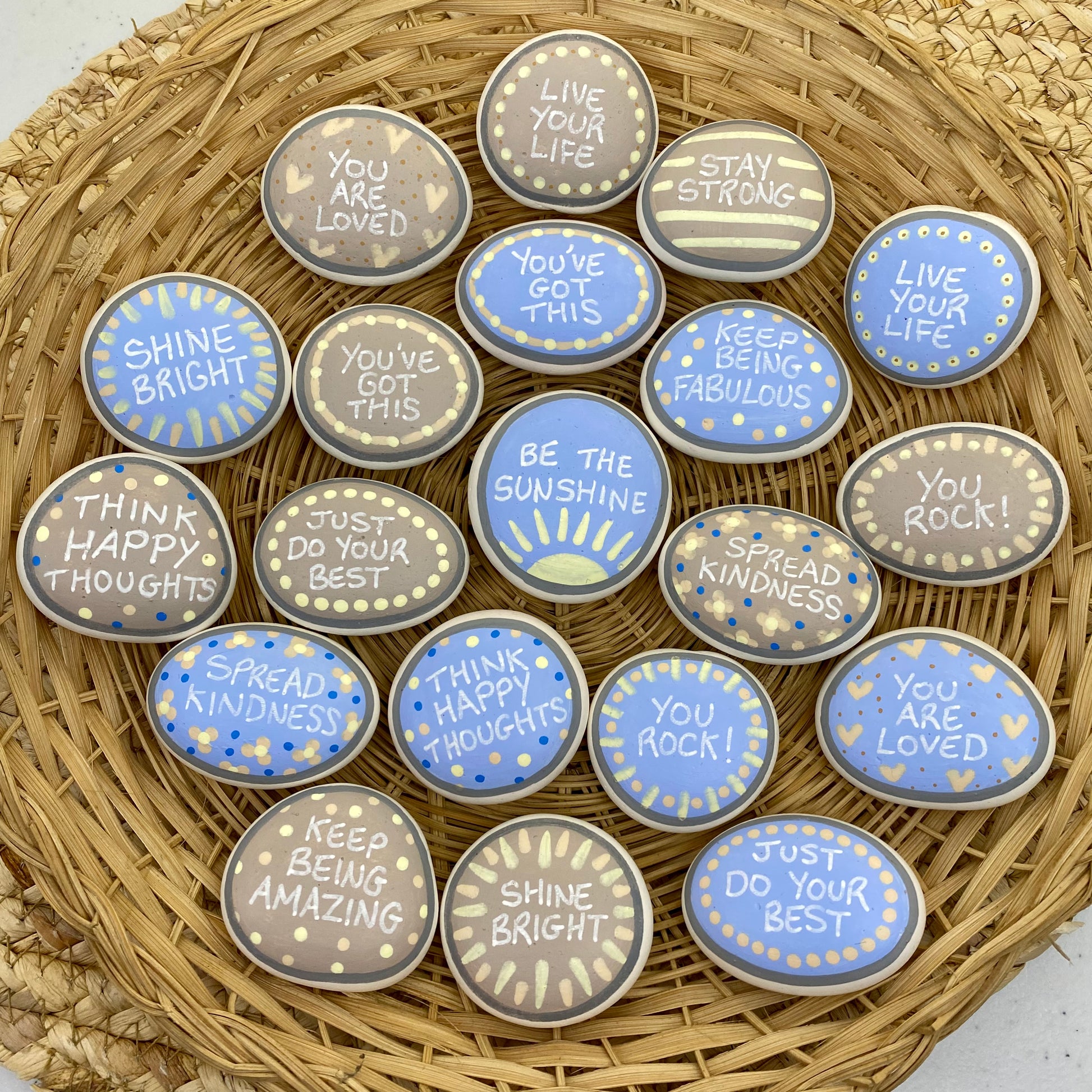 Lots of Pastel Blue and Beige Hand painted pebbles with uplifting affirmations written on