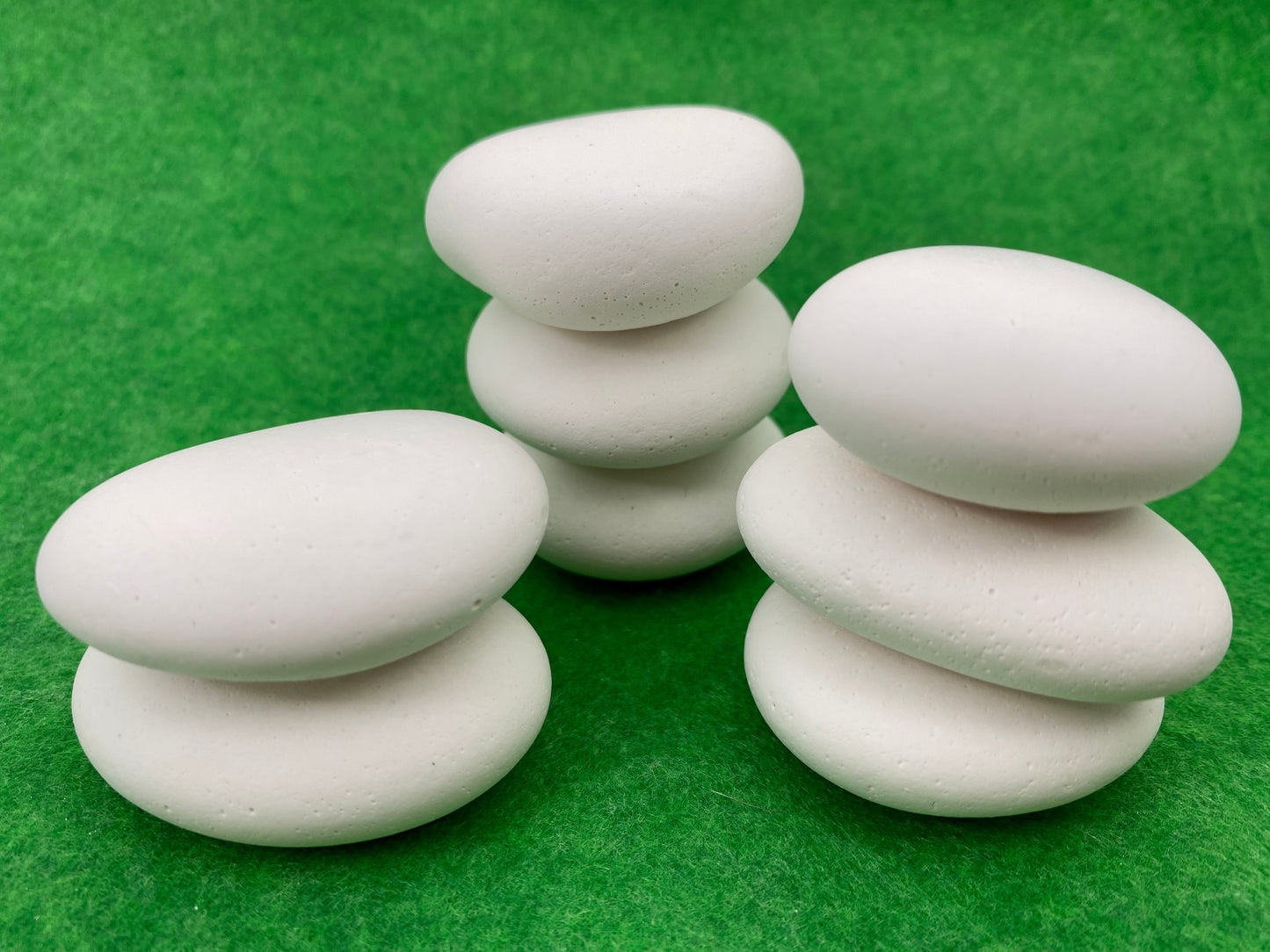 8 small white plaster pebbles of different shapes and sizes stacked on top of each other