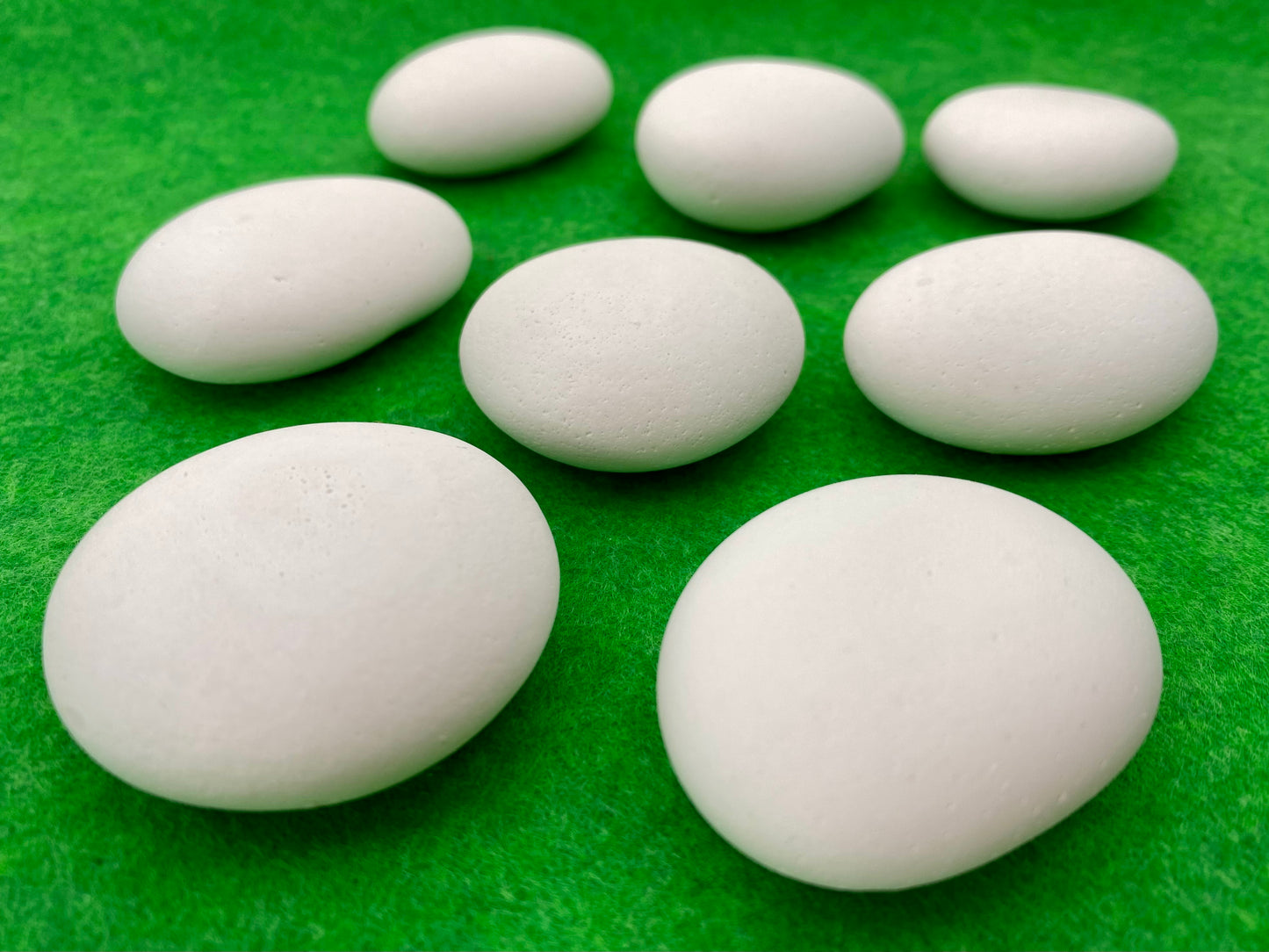 8 small white plaster pebbles of different shapes and sizes