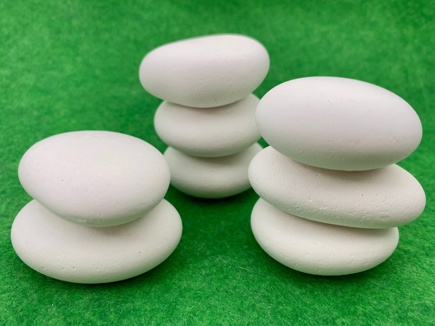 8 small white plaster pebbles of different shapes and sizes stacked on top of each other