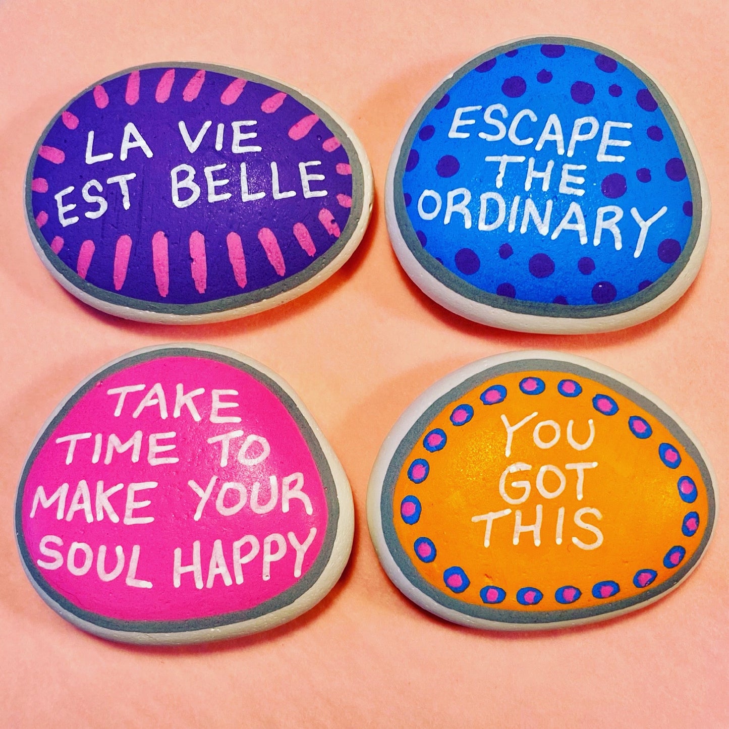 Colourful Hand painted pebbles with uplifting affirmations written on