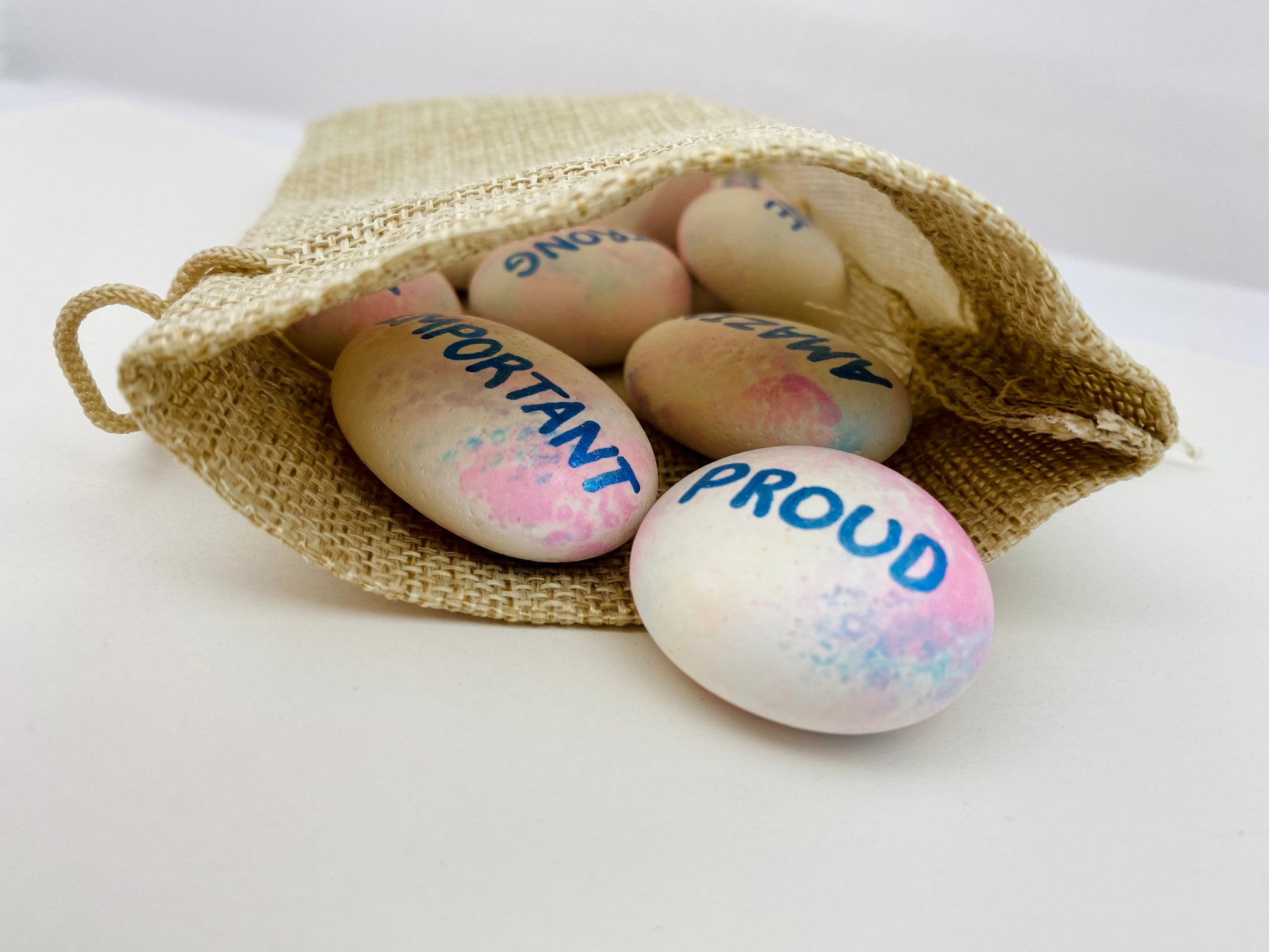 A hessian bag with hand painted affirmation pebbles spilling out