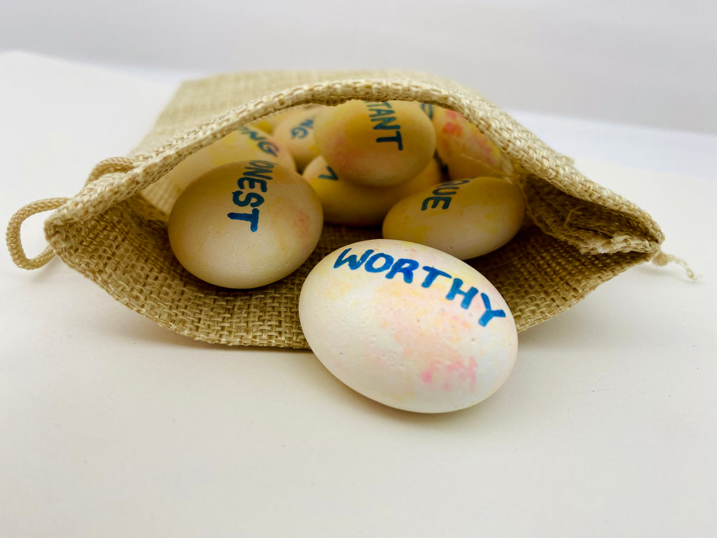 A hessian bag with hand painted affirmation pebbles spilling out