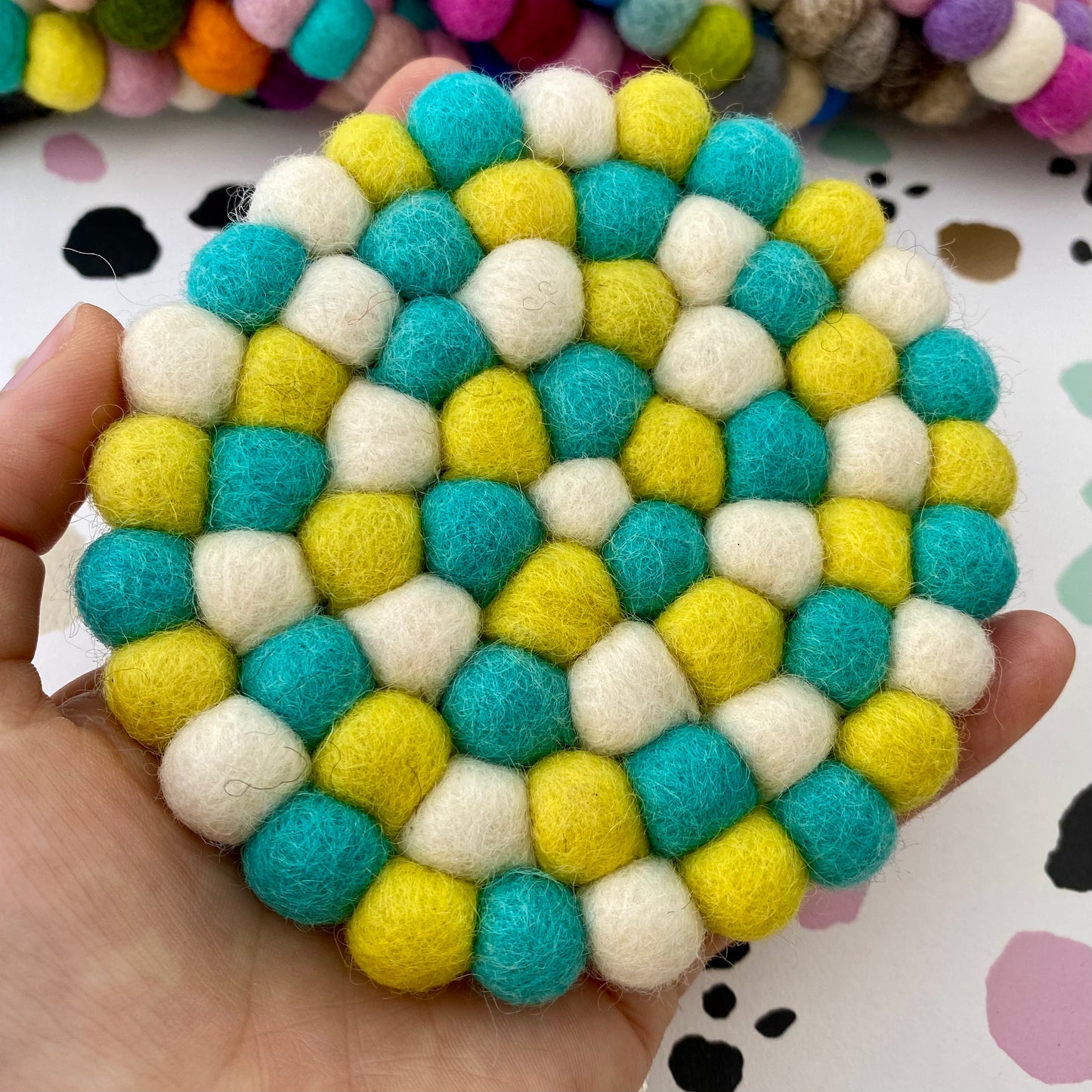 Colourful Coaster sized Mat made from Felt Balls in Green, Yellow and White.