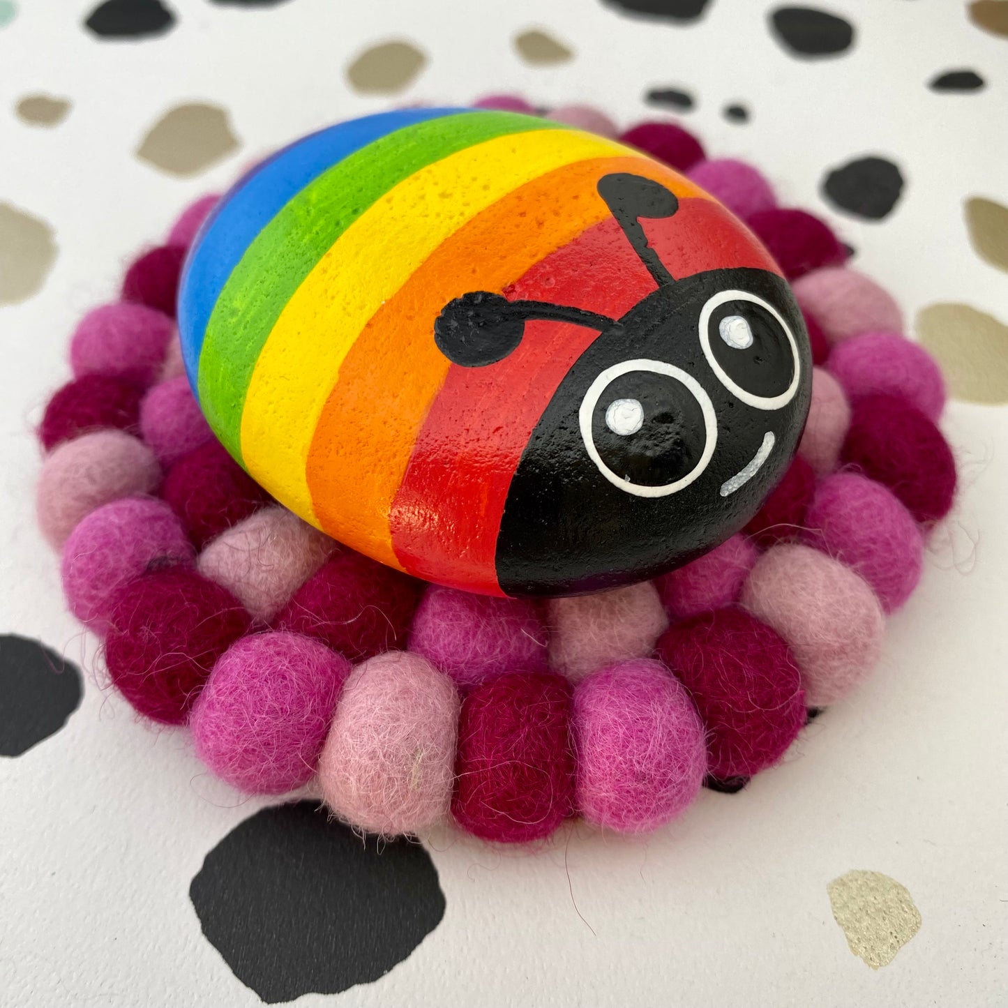 Coaster sized Mat made from Pink Felt Balls with a Hand painted Rainbow Bug Pebble on top