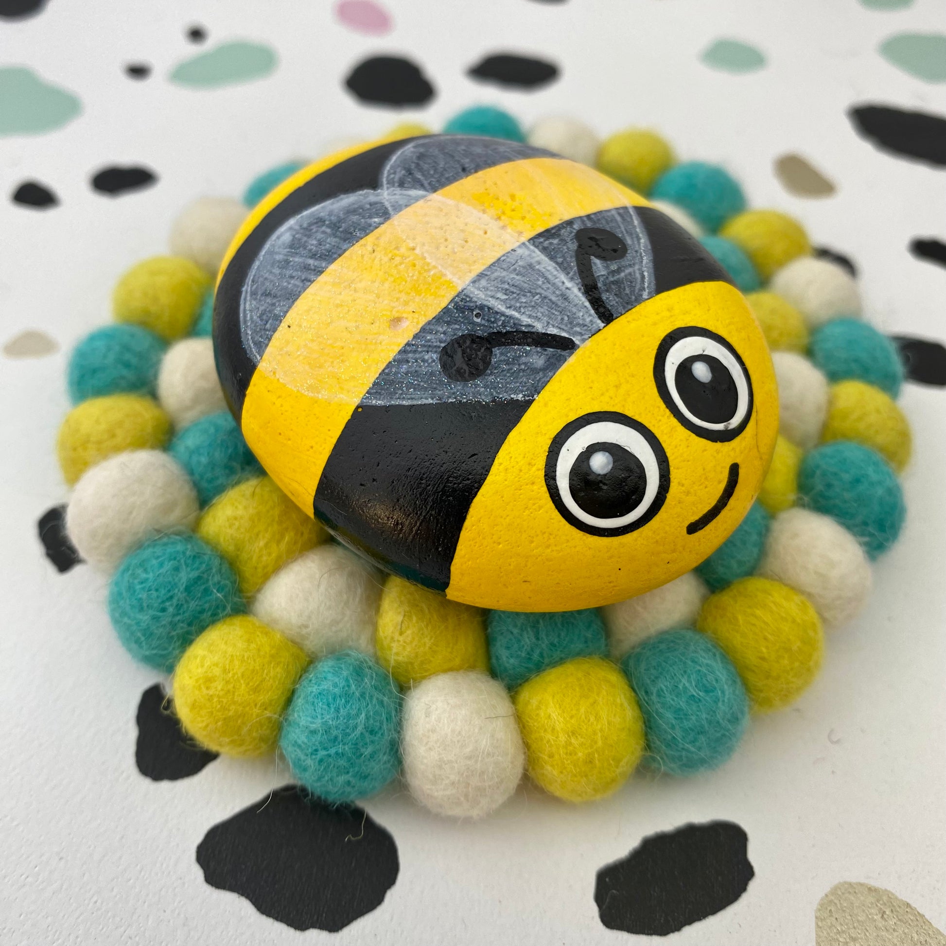 Coaster sized Mat made from Green, Yellow and White Felt Balls with a Hand painted Bee Pebble on top