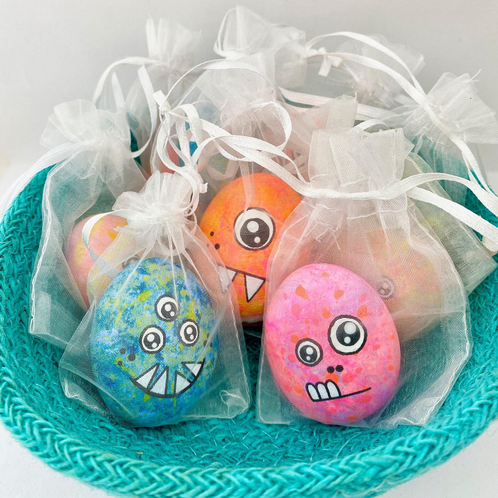 Lots of hand painted Pocket Monster pebbles in organza bags in a bowl