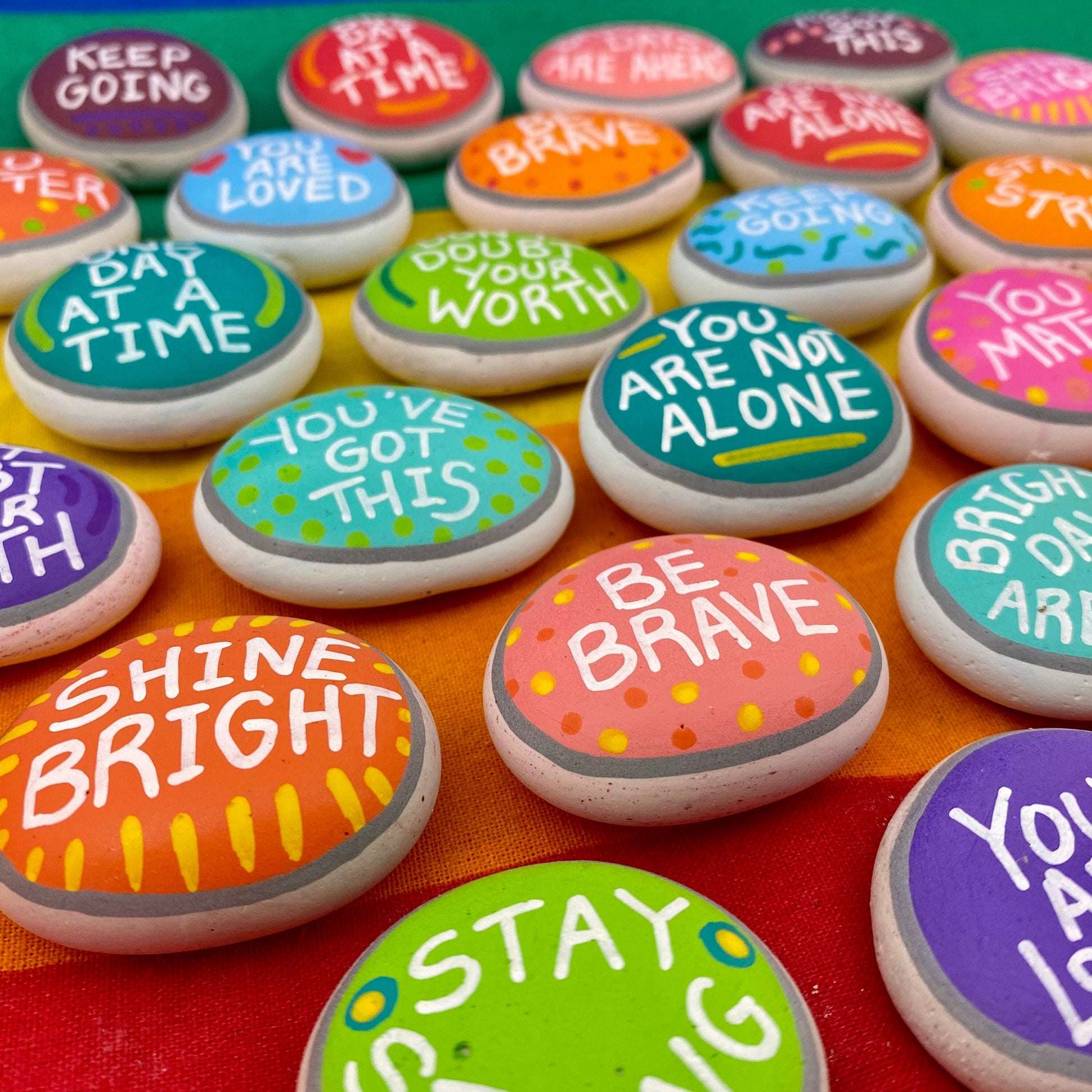Lots of Colourful Hand painted pebbles with uplifting affirmations written on